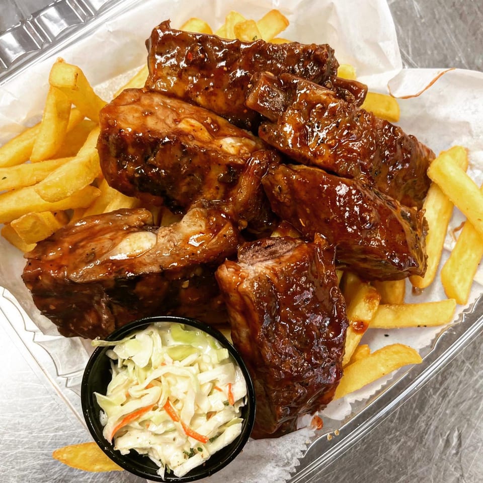 BBQ ribs with french fries and coleslaw in a plastic takeout container from Fireman's Cafe.
