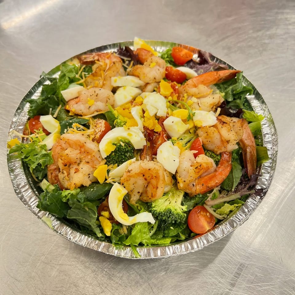 A vibrant shrimp salad from Fireman's Cafe, with lettuce, tomatoes, broccoli, and hard-boiled eggs.