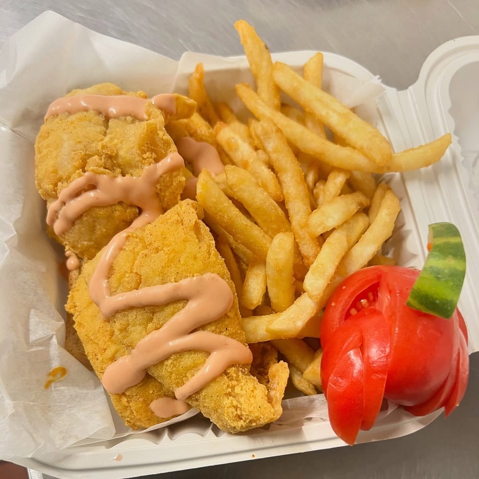 Fireman's Cafe fried fish and french fries with pink sauce and a carved tomato.