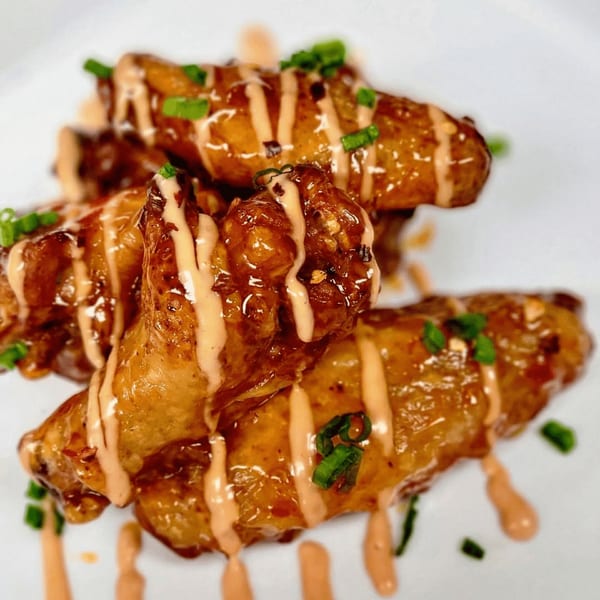 Fireman's Cafe's glazed chicken wings drizzled with sauce and garnished with green onions.