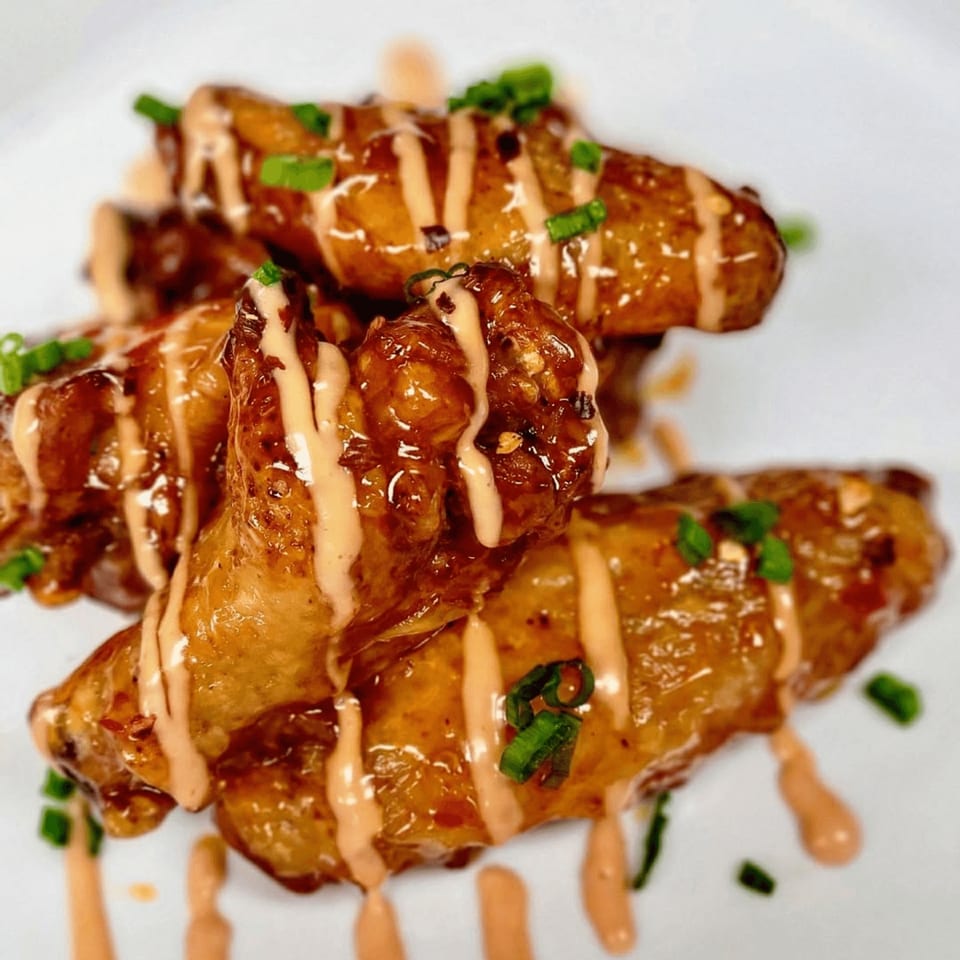 Fireman's Cafe's glazed chicken wings drizzled with sauce and garnished with green onions.